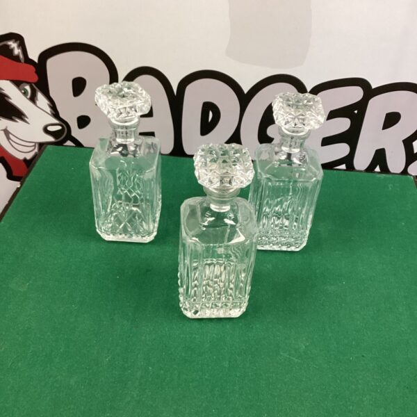 Three vintage glass decanters with faceted designs on a dark background.