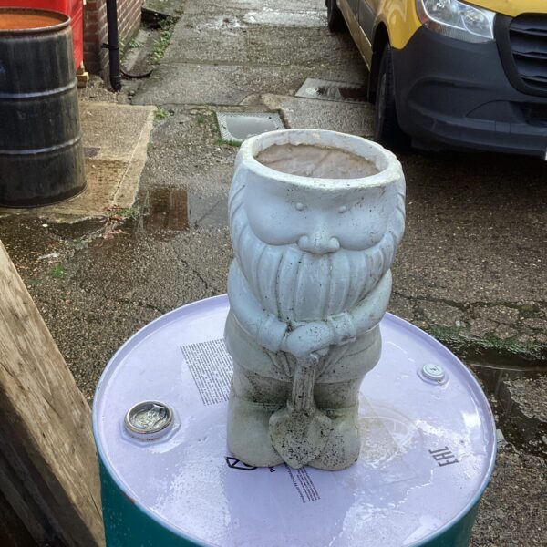 Vintage ceramic garden gnome flower pot in a garden setting.