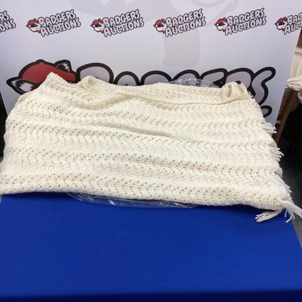 Cream wool blanket with fringed edges for home decor.
