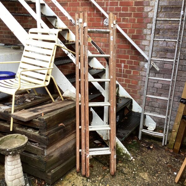 Vintage wooden and aluminium three-piece ladder in a garden setting.