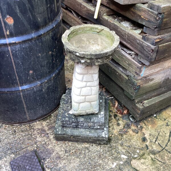 Weathered stone bird bath in a garden setting.