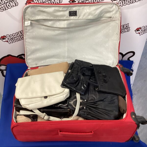 Red suitcase filled with assorted vintage handbags and purses.