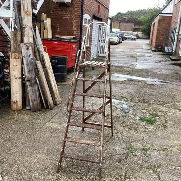 Vintage wooden step ladder leaning against a brick wall.