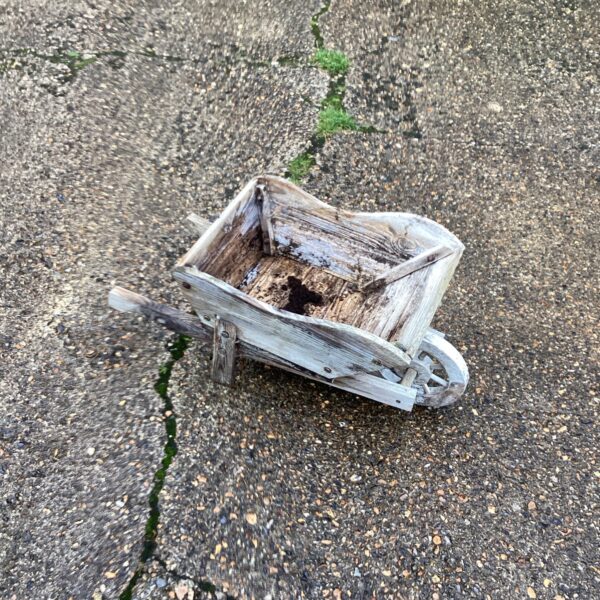 Rustic wooden wheelbarrow planter for garden decor.