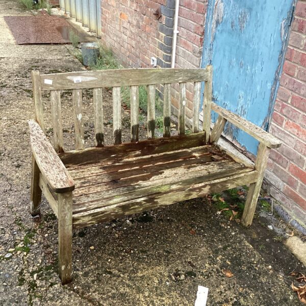 Weathered wooden garden bench in a garden setting.