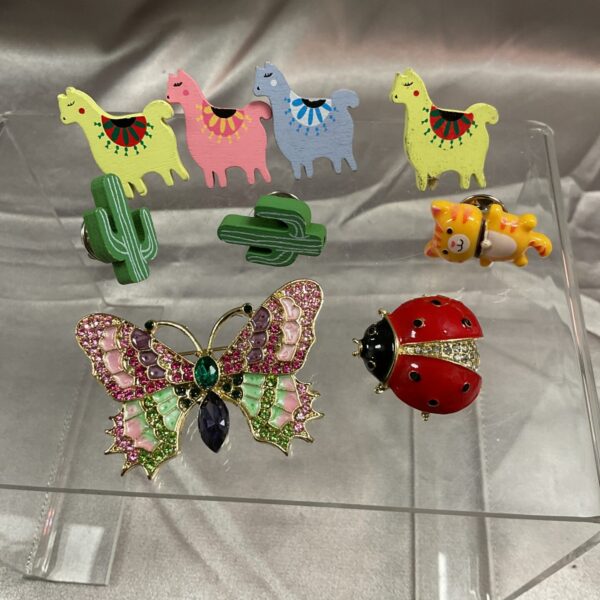 Colourful brooch collection featuring animal and botanical designs.