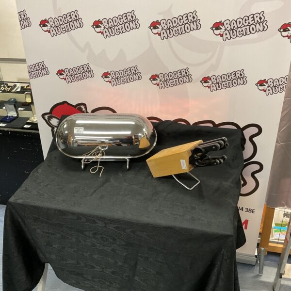 Vintage stainless steel bread bin with knife set on display.
