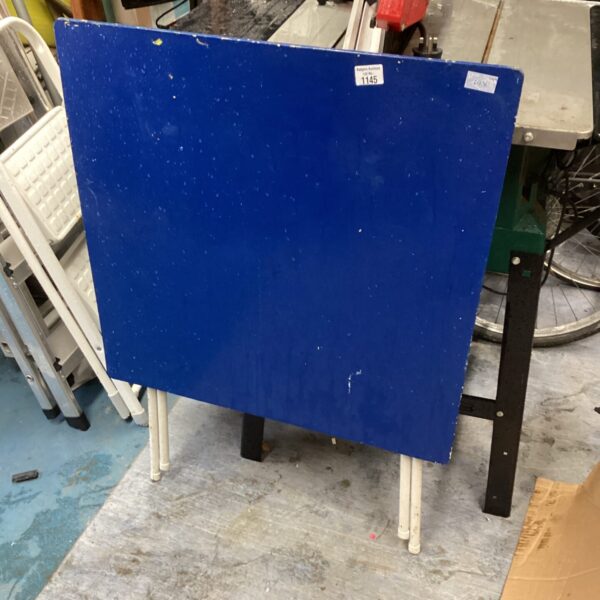 Blue folding table with metal legs, side view.