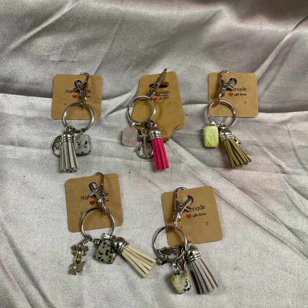 Set of five handmade polished stone keyrings with varied patterns.