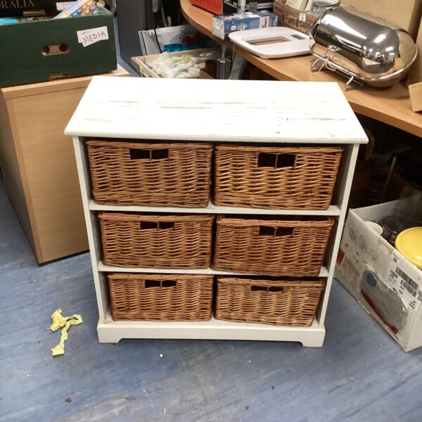 White repurposed storage unit with wicker baskets for home organisation.