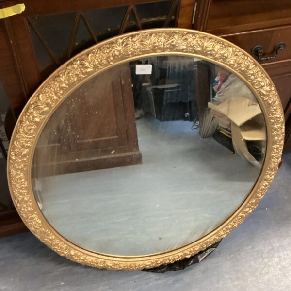 Ornate gilt framed circular mirror for wall decoration.