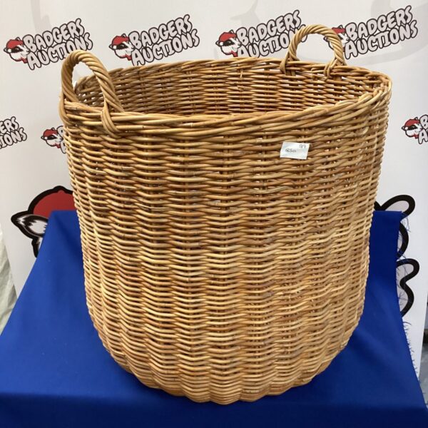 Large wicker log basket for firewood storage near a fireplace.
