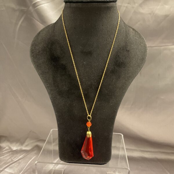 Close-up of vintage red faceted pendant necklace on a display.