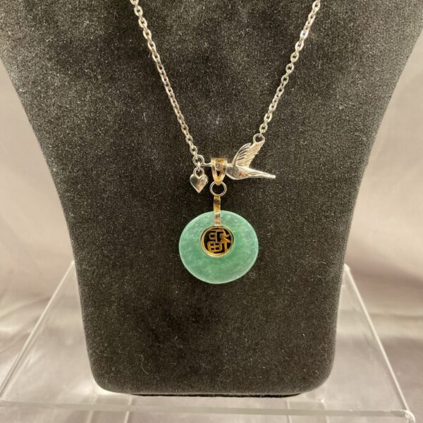 Close-up of a jade pendant on a silver necklace.