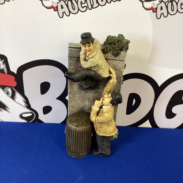 Vintage Laurel and Hardy figurine climbing a wall.