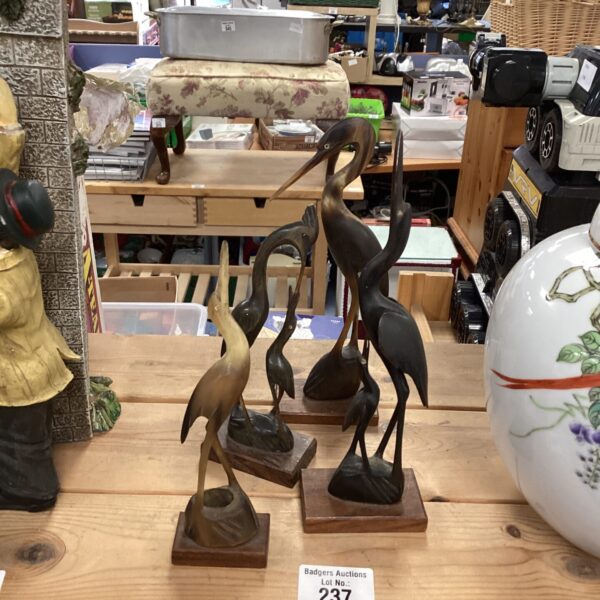 Group of four carved horn crane bird figurines on wooden bases.
