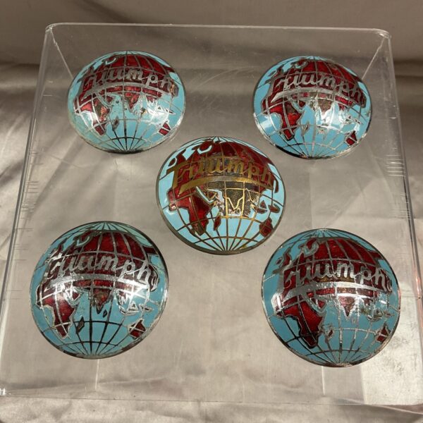 Group of five vintage Triumph Globe wheel hub badges.