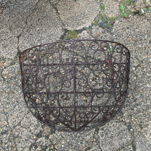 Antique wrought iron hanging hay feeder with decorative swirls.
