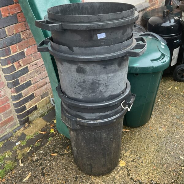 Stack of four black plastic storage bins for garden or utility use.
