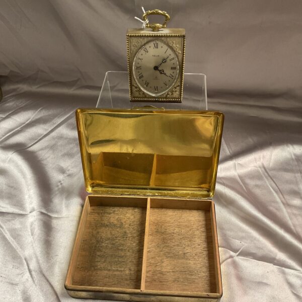 Vintage brass mantle clock and State Express cigarette box set on display.