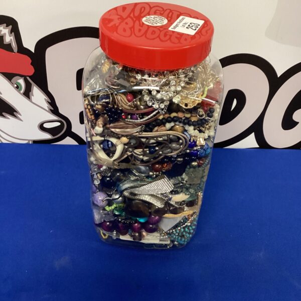 Colourful jar filled with mixed costume jewellery pieces.