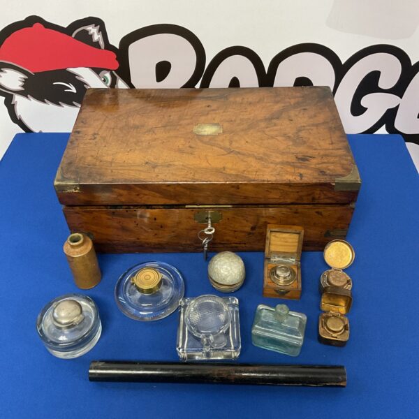 Antique vintage writing slope with collection of inkwells displayed.