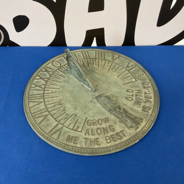 Vintage metal sundial with Roman numerals in a garden setting.