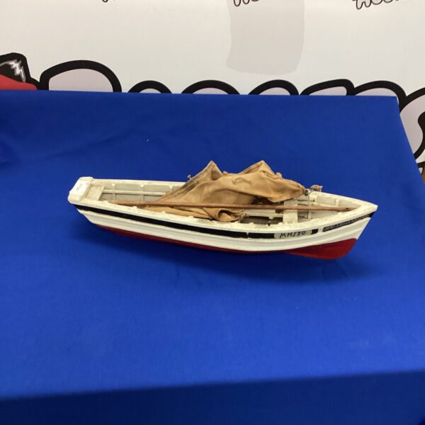 Vintage model fishing boat with weathered paint and wooden hull.