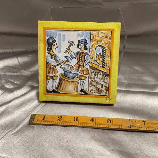 Vintage Spanish pottery tile depicting blacksmiths working at a forge.
