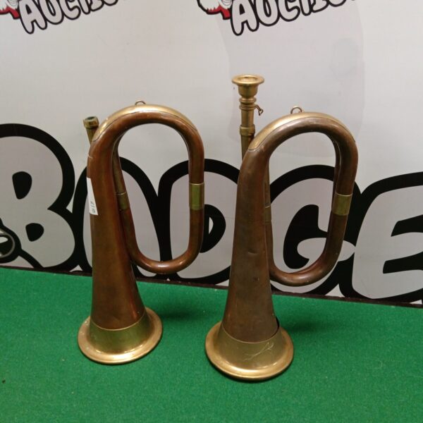Two vintage brass and copper bugles, antique musical instruments.