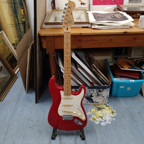 Red Fender Squire Stratocaster electric guitar on display.