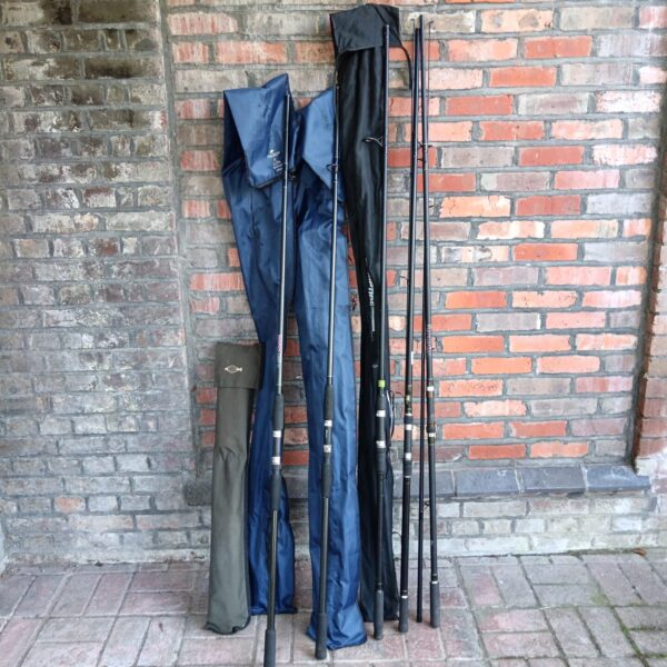 Lot of five carp fishing rods and a rod pod against a brick wall.
