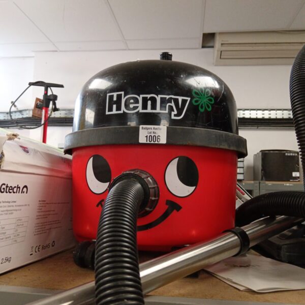 Red Numatic Henry vacuum cleaner with cheerful face.