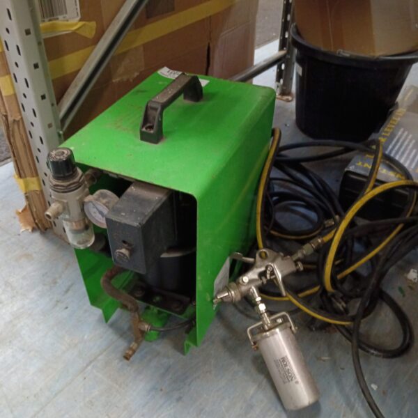 Small green portable air compressor with fittings and gauge.