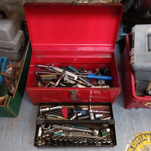 Vintage red metal toolbox filled with various hand tools.