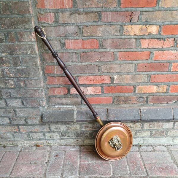 Antique copper bed pan with ornate lion head detail.