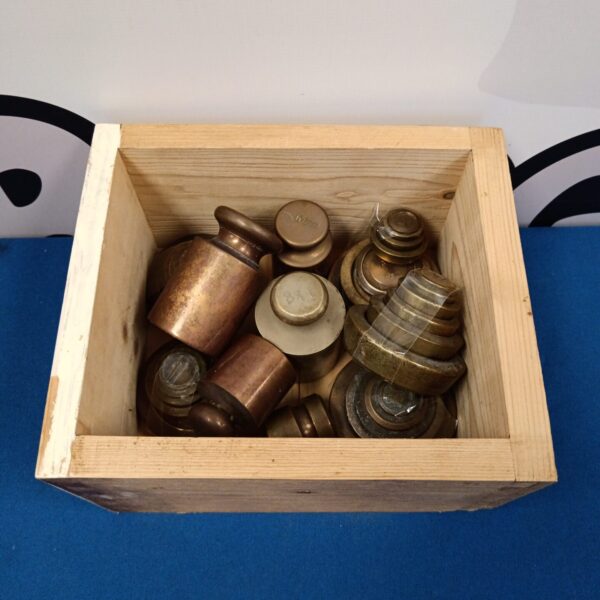 Collection of vintage brass scale weights in a wooden box.