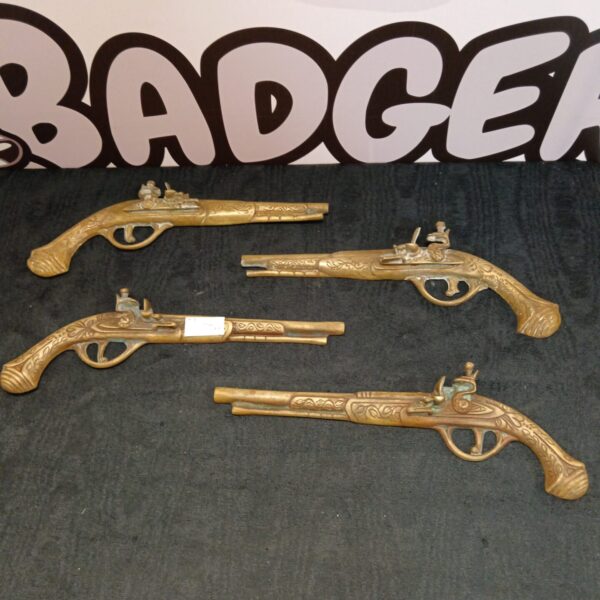 Pair of decorative brass flintlock pistols for wall display.