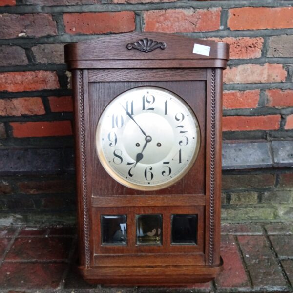 Vintage wooden wall clock with pendulum and Roman numerals.