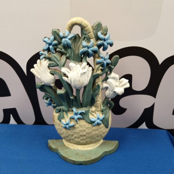 Vintage cast iron flower doorstop with white and blue blooms.