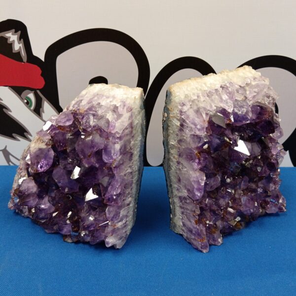 Large amethyst crystal bookends with purple geodes on a blue surface.