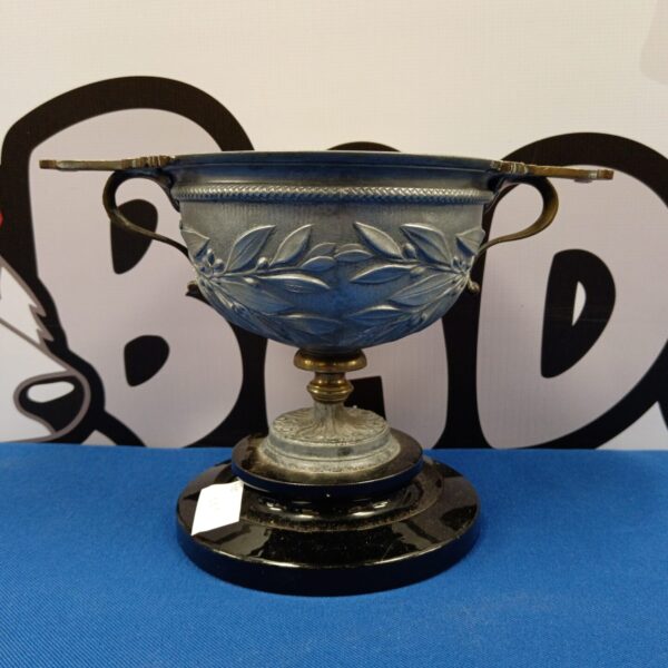 Antique pewter trophy with embossed leaf pattern on wooden base.