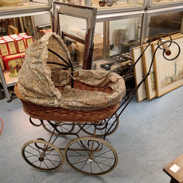 Antique Victorian doll pram with wicker basket and metal frame.
