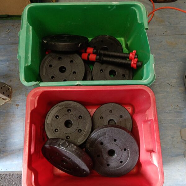 Black dumbbell set with weight plates in a green box.