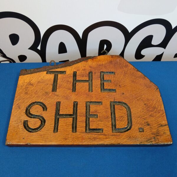 Front view of a vintage wooden shed sign with raised lettering.