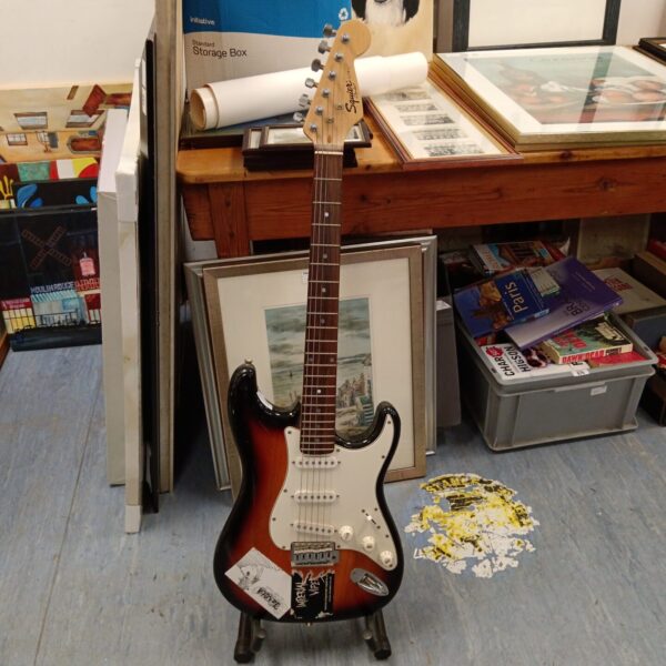 Sunburst Fender Squire Stratocaster electric guitar displayed indoors.