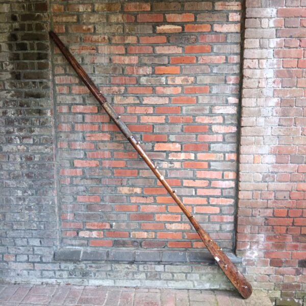 Antique boat oar repurposed as a unique coat rack for nautical decor.