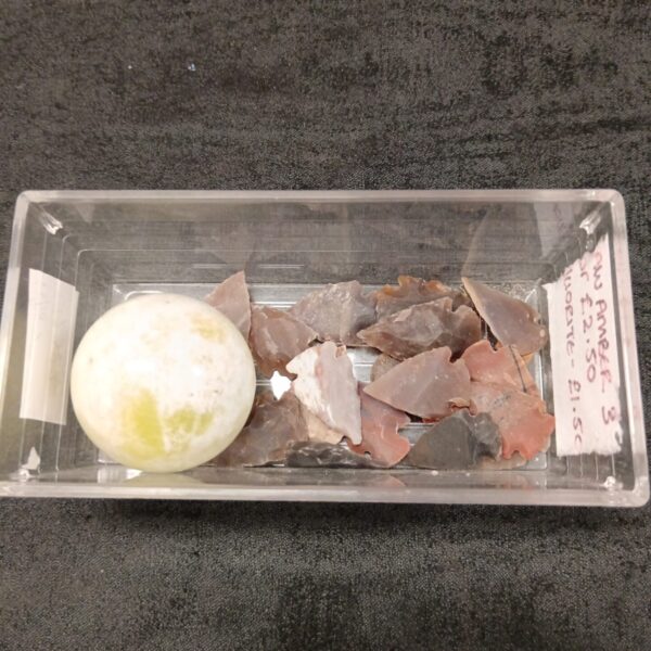 Collection of ancient stone arrowheads and a marble ball.