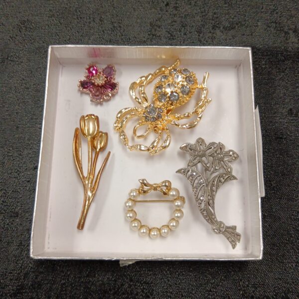 Close-up of a vintage spider brooch in a brooch lot.