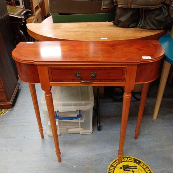 Walnut effect hall table with curved front and single drawer.